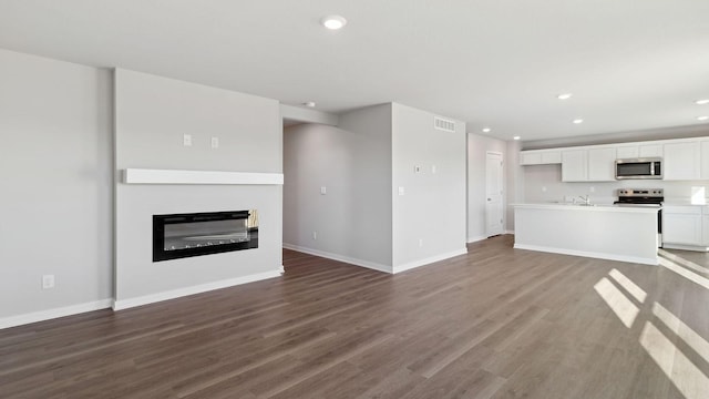 unfurnished living room with recessed lighting, baseboards, dark wood-style flooring, and visible vents