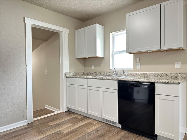 kitchen featuring visible vents, white cabinetry, a sink, light wood finished floors, and dishwasher
