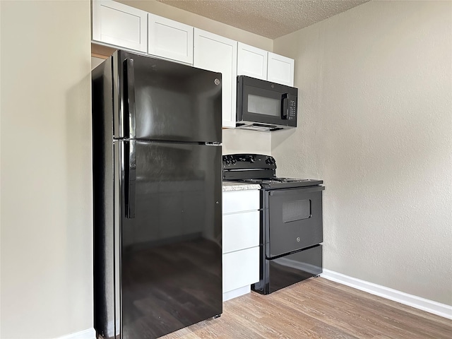 kitchen with light wood-style floors, light countertops, white cabinetry, baseboards, and black appliances