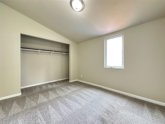 unfurnished bedroom featuring a closet, baseboards, carpet flooring, and lofted ceiling