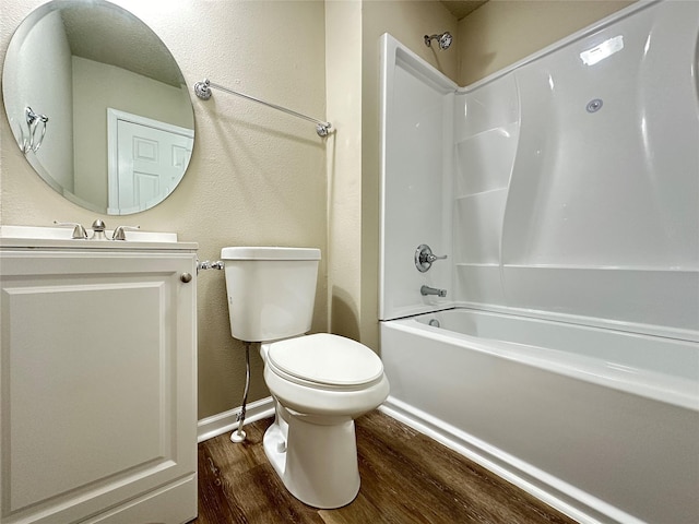 full bathroom with a textured wall, wood finished floors, toilet, baseboards, and shower / washtub combination
