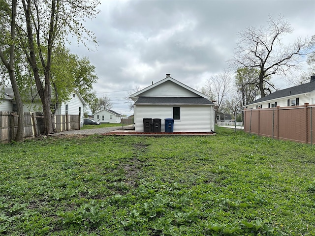 rear view of house featuring a fenced backyard and a yard