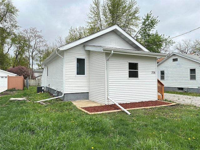 back of property with a lawn, central AC, and fence