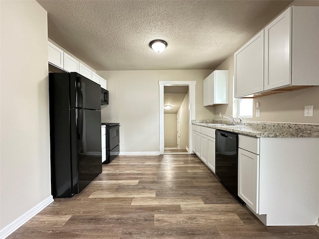 kitchen with a sink, white cabinetry, black appliances, and light countertops