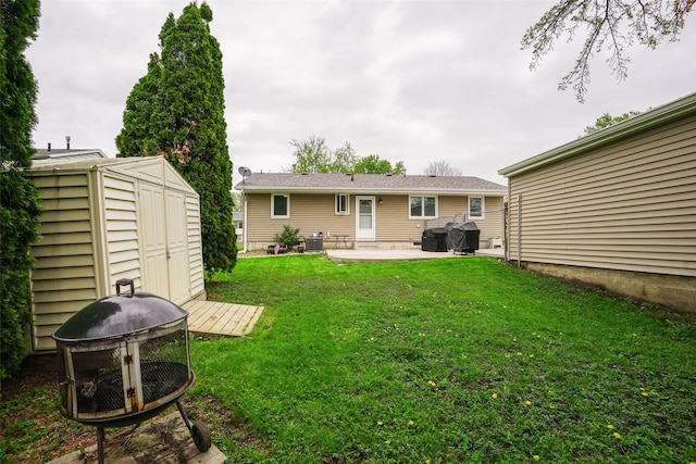 back of house featuring an outbuilding, a patio area, an outdoor fire pit, a yard, and a storage unit