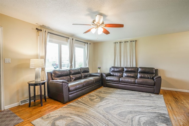 living area with a ceiling fan, baseboards, wood finished floors, and a textured ceiling