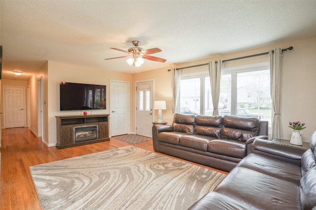 living room with baseboards, a ceiling fan, a textured ceiling, and wood finished floors