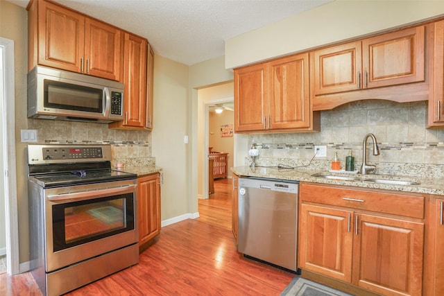 kitchen featuring a sink, light wood-style flooring, appliances with stainless steel finishes, and backsplash