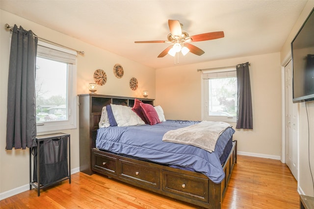 bedroom featuring light wood-style floors, baseboards, a ceiling fan, and a closet