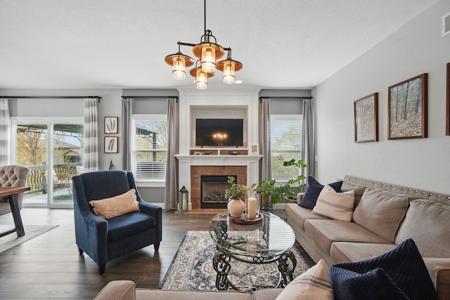 living room with a chandelier, a wealth of natural light, visible vents, and wood finished floors