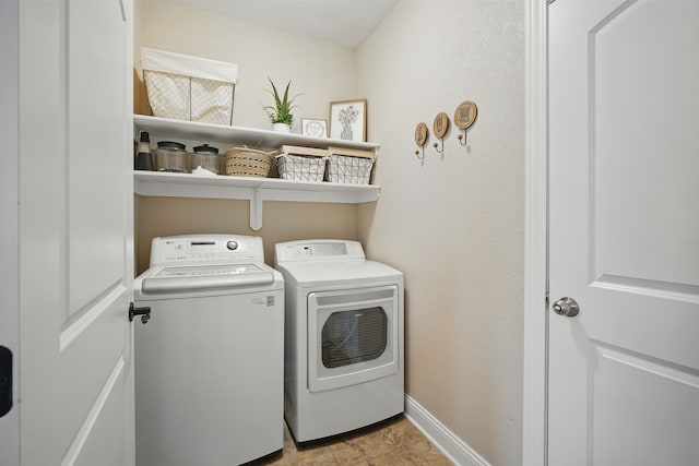 clothes washing area featuring laundry area, baseboards, and washing machine and clothes dryer