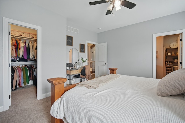 bedroom featuring a closet, carpet floors, visible vents, baseboards, and a walk in closet