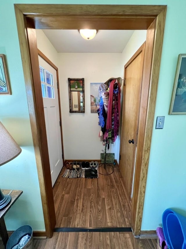 doorway featuring baseboards and wood finished floors
