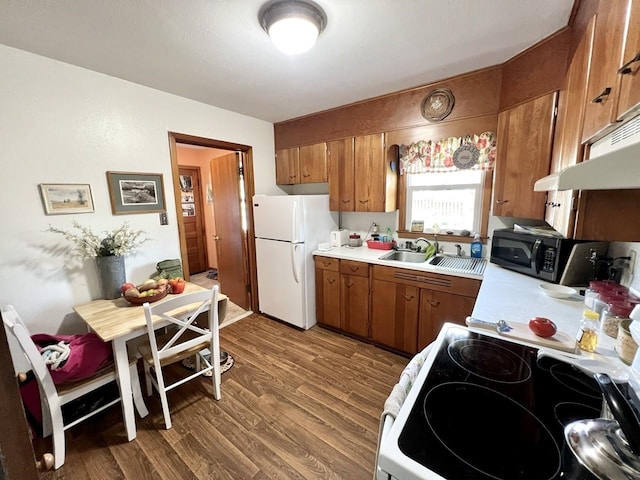 kitchen featuring light countertops, wood finished floors, brown cabinets, and white appliances
