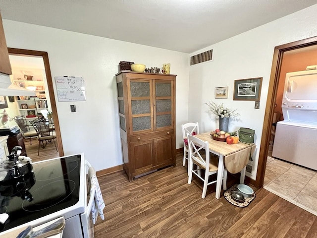dining space featuring baseboards, stacked washer and clothes dryer, wood finished floors, and visible vents