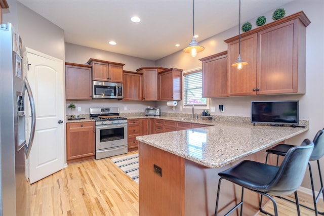 4208 SW Camden Ridge Dr, Ankeny, IA 50023 - kitchen with stainless steel appliances, a peninsula, light wood-type flooring, brown cabinetry, and light stone countertops