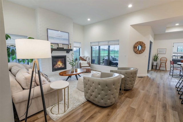living room featuring a large fireplace, recessed lighting, and wood finished floors