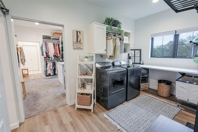 clothes washing area with washing machine and clothes dryer, recessed lighting, light wood-style flooring, and cabinet space