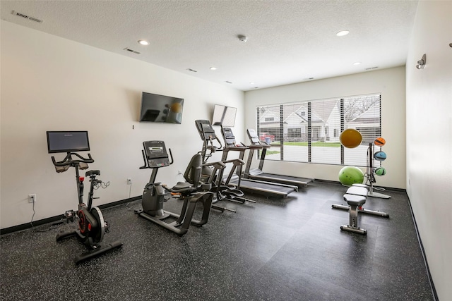 exercise room featuring baseboards, a textured ceiling, and visible vents