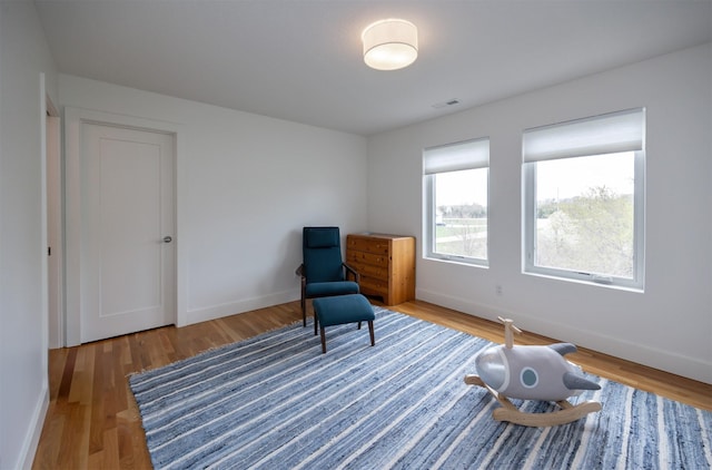 sitting room with visible vents, baseboards, and wood finished floors