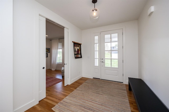doorway to outside featuring baseboards and wood finished floors