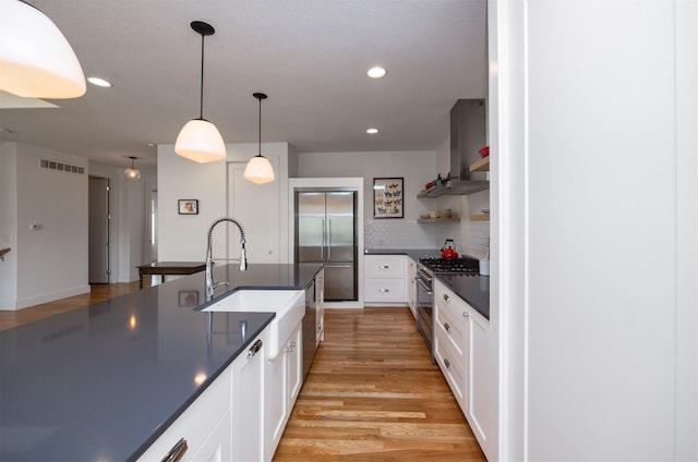 kitchen featuring visible vents, dark countertops, white cabinetry, a sink, and appliances with stainless steel finishes