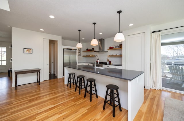 kitchen featuring dark countertops, plenty of natural light, open shelves, and wall chimney exhaust hood
