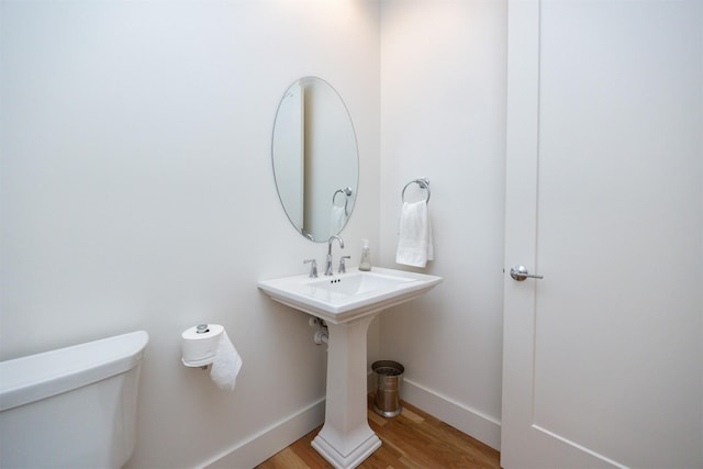 half bathroom featuring baseboards, toilet, and wood finished floors