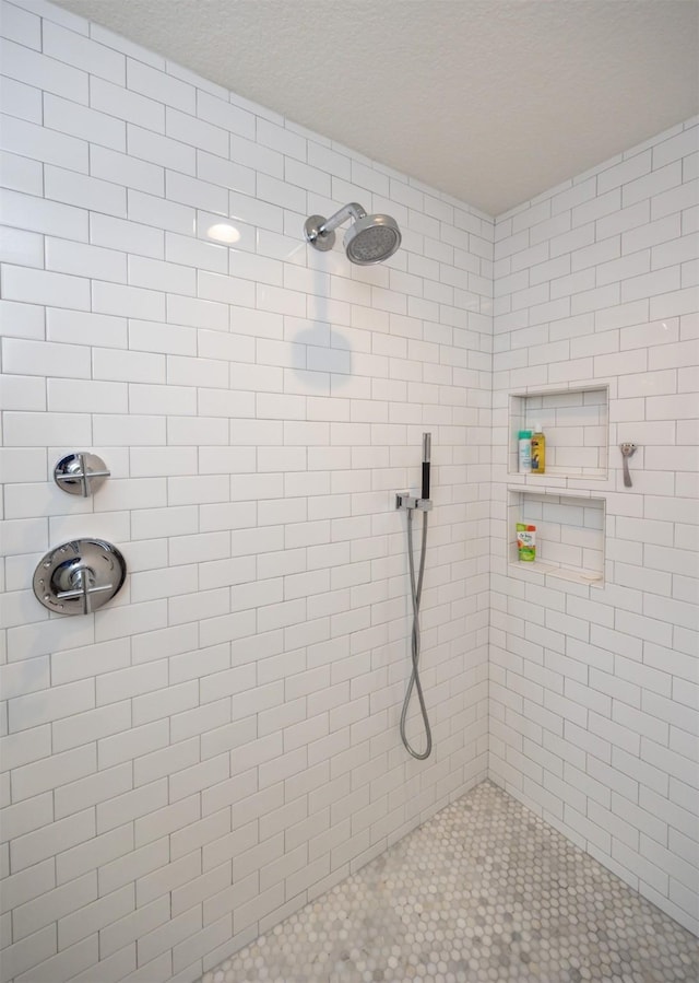 bathroom featuring a textured ceiling and tiled shower