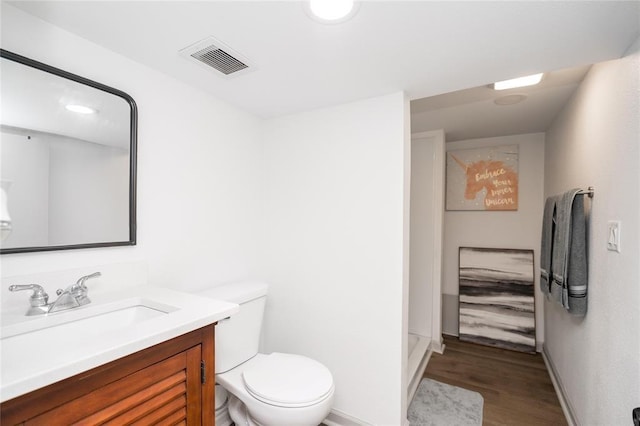 full bath with visible vents, wood finished floors, vanity, baseboards, and toilet