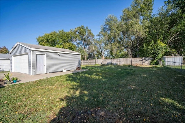 view of yard with a fenced backyard, an outbuilding, and a detached garage