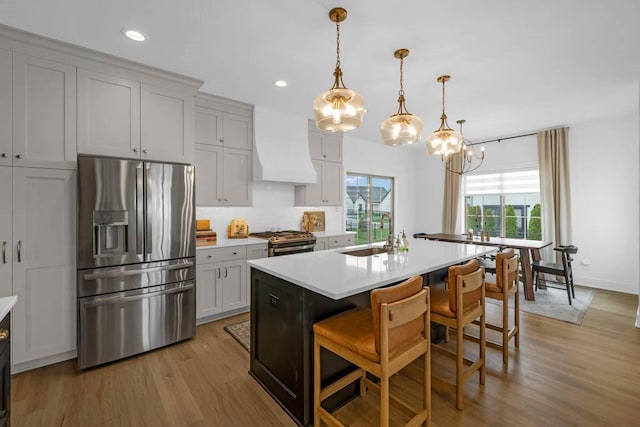 kitchen with custom exhaust hood, light countertops, a chandelier, a sink, and appliances with stainless steel finishes