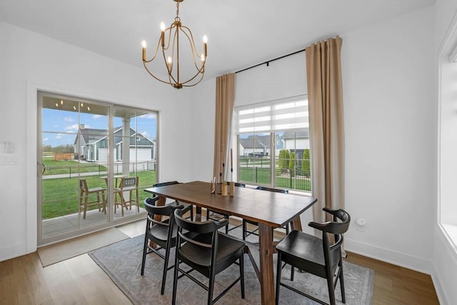 dining area with an inviting chandelier, wood finished floors, and a healthy amount of sunlight