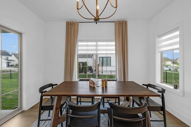 dining area with an inviting chandelier, plenty of natural light, and wood finished floors