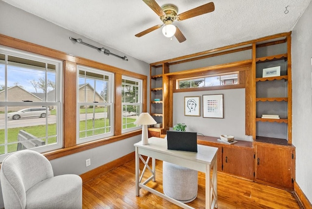 office area featuring plenty of natural light, a ceiling fan, light wood-style flooring, and baseboards