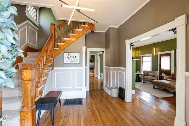stairway featuring crown molding, wainscoting, and wood finished floors