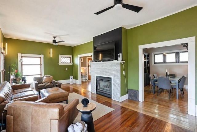 living area featuring wood-type flooring, ceiling fan, a wealth of natural light, and a tile fireplace