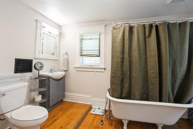 full bathroom with vanity, wood finished floors, toilet, baseboards, and a freestanding bath