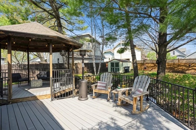 deck with a fenced backyard, an outbuilding, a gazebo, and a shed