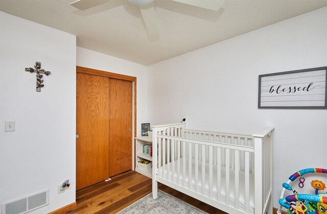 520 SE Murphy Dr, Waukee, IA 50263 - bedroom featuring a nursery area, ceiling fan, visible vents, and wood finished floors