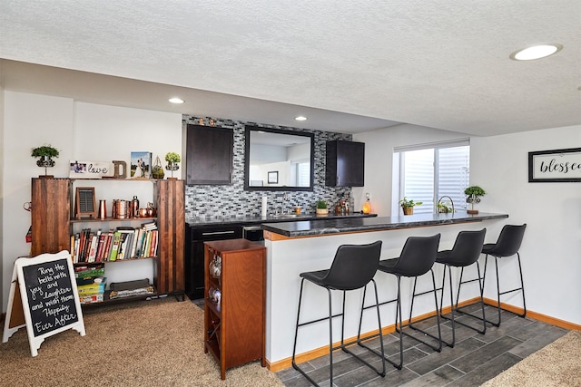 520 SE Murphy Dr, Waukee, IA 50263 - kitchen with decorative backsplash, dark countertops, a kitchen breakfast bar, recessed lighting, and a textured ceiling