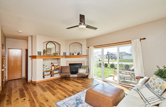 520 SE Murphy Dr, Waukee, IA 50263 - living area featuring a textured ceiling, ceiling fan, wood finished floors, and a fireplace