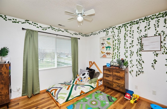 520 SE Murphy Dr, Waukee, IA 50263 - bedroom with a textured ceiling, a ceiling fan, baseboards, wood finished floors, and visible vents