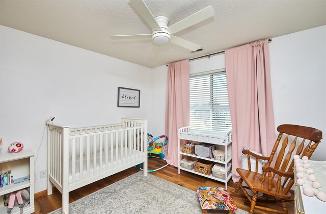520 SE Murphy Dr, Waukee, IA 50263 - bedroom featuring a nursery area, ceiling fan, and wood finished floors