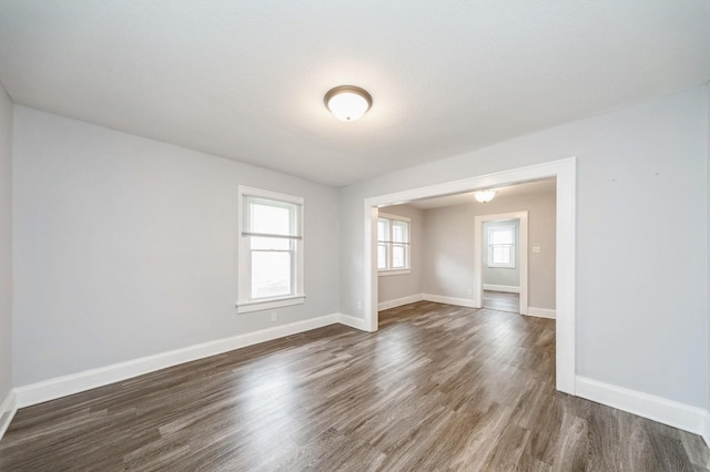 empty room featuring baseboards and dark wood-style floors