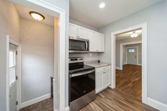 kitchen featuring baseboards, wood finished floors, white cabinets, and stainless steel appliances