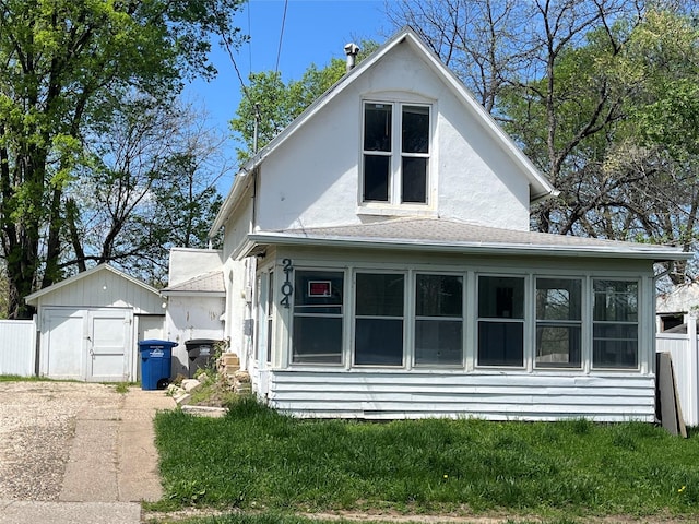 back of house with stucco siding, fence, an outdoor structure, and a storage unit