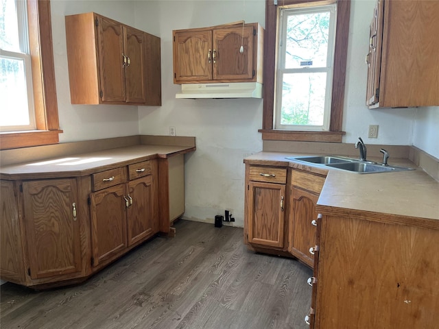 2104 23rd St, Des Moines, IA 50310 - kitchen with brown cabinetry, a sink, light countertops, light wood finished floors, and under cabinet range hood
