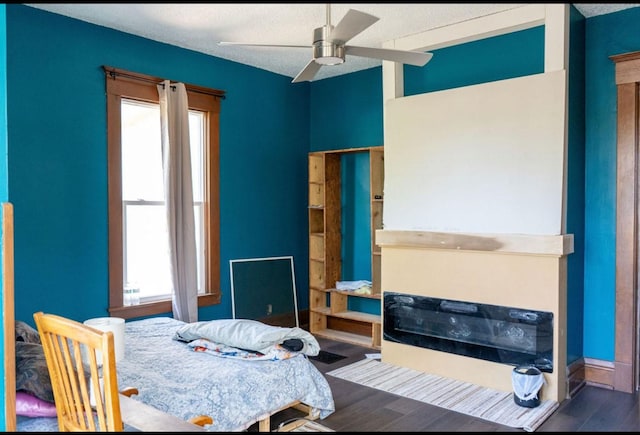 bedroom featuring baseboards, a ceiling fan, a textured ceiling, and wood finished floors