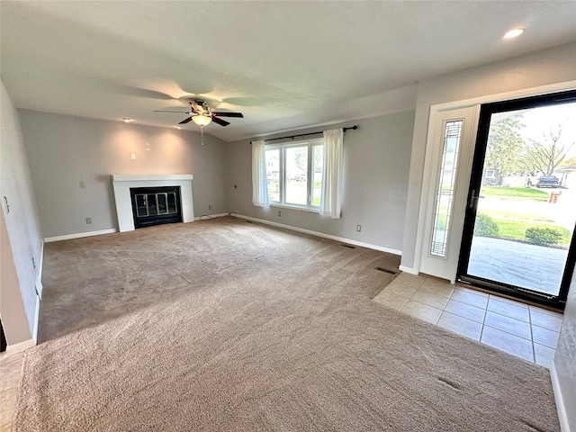 unfurnished living room with visible vents, a glass covered fireplace, baseboards, ceiling fan, and carpet